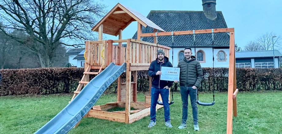 Den symbolischen Fördersscheck nahmen Mario Becker (l.) und Björn Stoff vom Kapellenverein Kerperscheid entgegen.